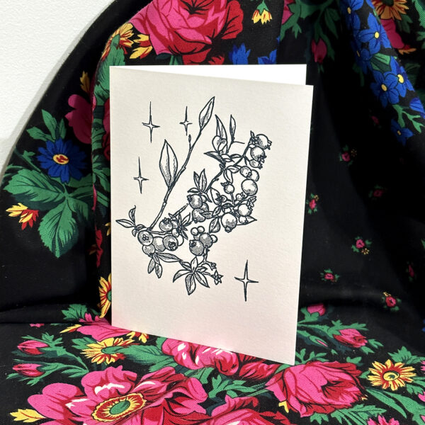 A photo of a white printed card standing on dark fabric
