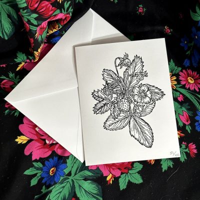 A photo of a white printed card and envelope on dark fabric